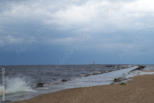 sea shore with lighthouse in distance during stromy day.
