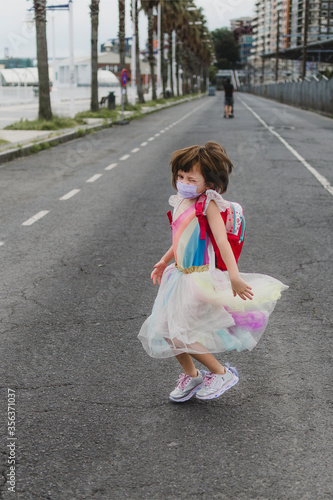 Niña disfrazada con mascarilla en una calle vacía 