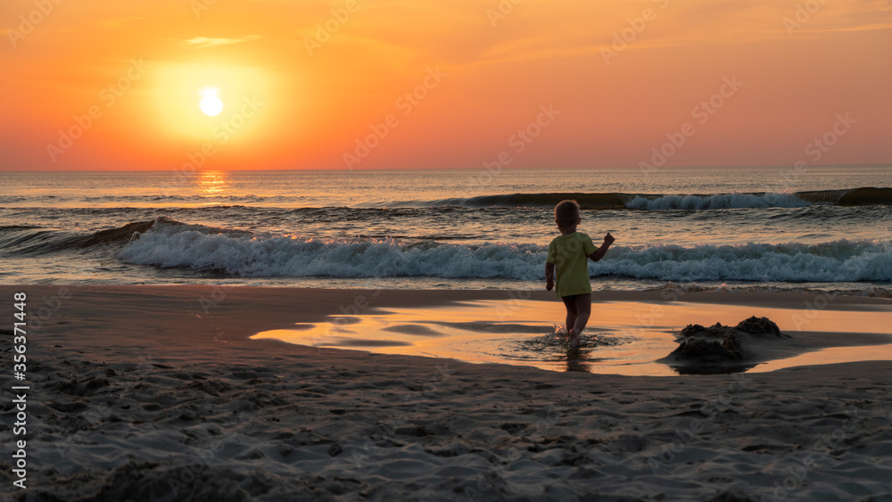 dziecko na plaży o zachodzie słońca