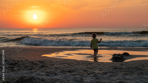 dziecko na plaży o zachodzie słońca