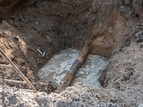 Foto damaged rusty water pipeline breaks in deep ditch trench