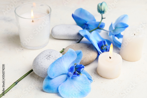 Beautiful orchid flowers, candles and stones on light background