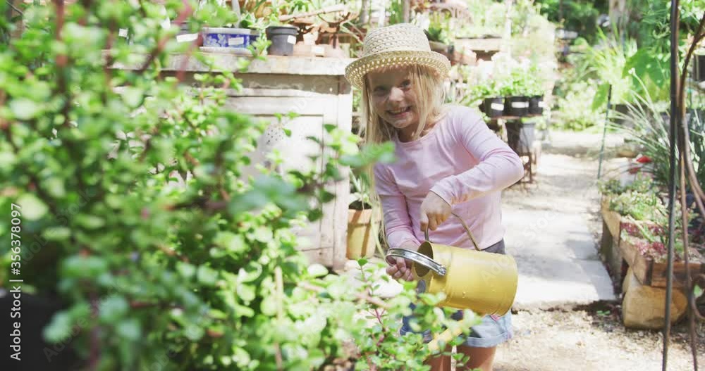 Little girl watering plants in a botanical garden Little girl watering plants in a botanical garden