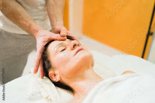Caucasian woman at massage salon having head treatment by professional physio therapist masseur