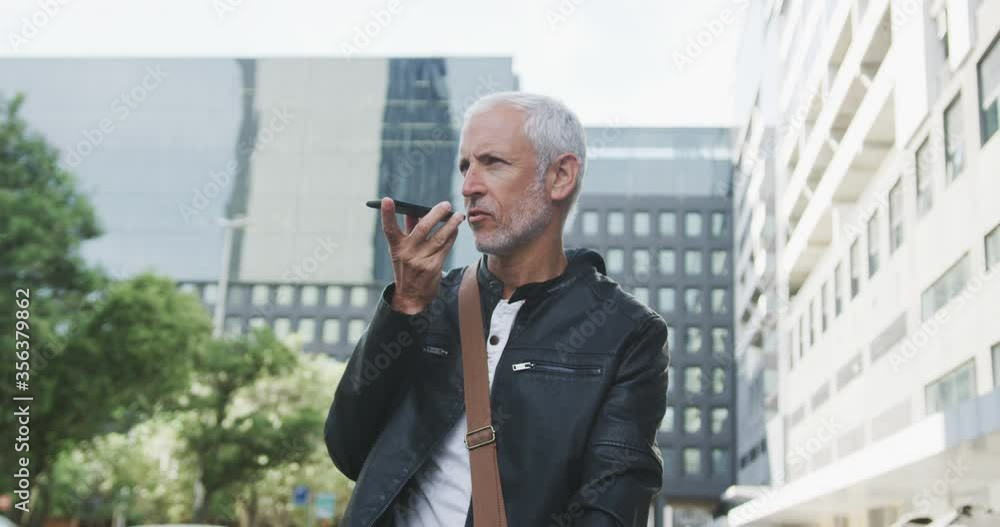 Caucasian man out and about in the city street talking on his smartphone Caucasian man out and about in the city street talking on his smartphone