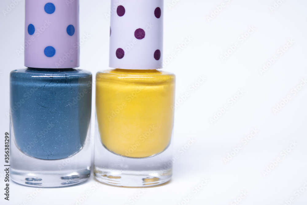 Bottles with blue and yellow nail polish on white background. nail lacquer. Nail manicure concept. Isolated, copy space. Bottles with blue and yellow nail polish on white background. nail lacquer. Nail manicure concept. Isolated, copy space.