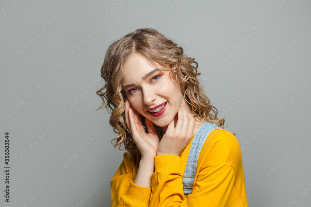 Young woman in yellow sweatshirt on gray background Young woman in yellow sweatshirt on gray background