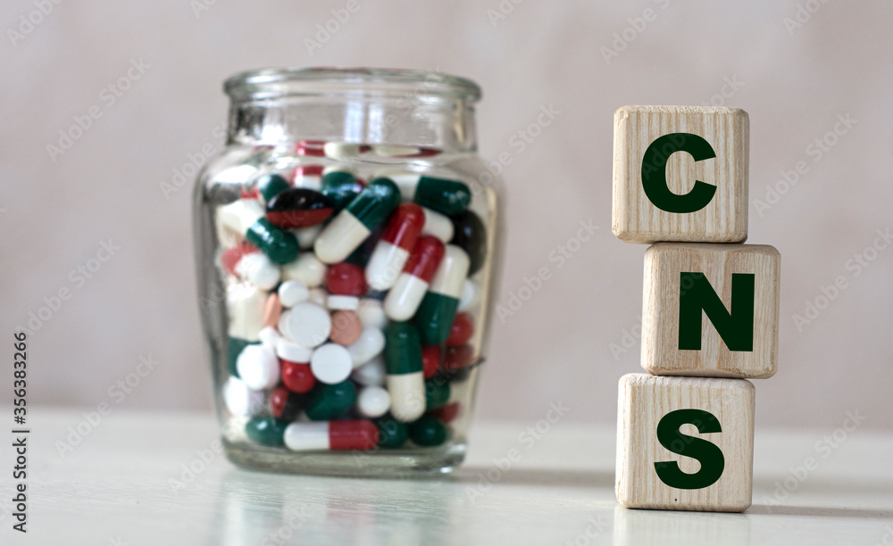 CNS (Central Nervous System) - acronym on cubes on a light background with a capacity with tablets CNS (Central Nervous System) - acronym on cubes on a light background with a capacity with tablets