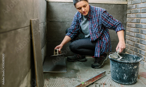 Foto Female mason laying a new tile floor on a terrace