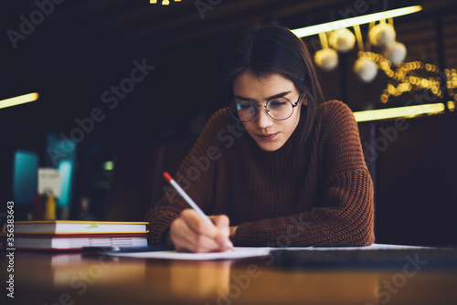 Female teenager preparing for exams while studying with books