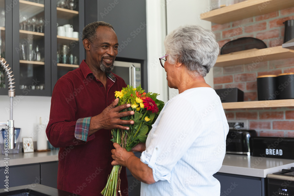Side view of senior African American man giving flower to his wife Side view of senior African American man giving flower to his wife
