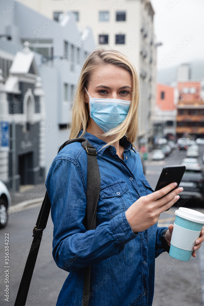 © Wavebreak Media - Caucasian woman wearing a covid19 coronavirus mask outside and using her phone © Wavebreak Media - Caucasian woman wearing a covid19 coronavirus mask outside and using her phone