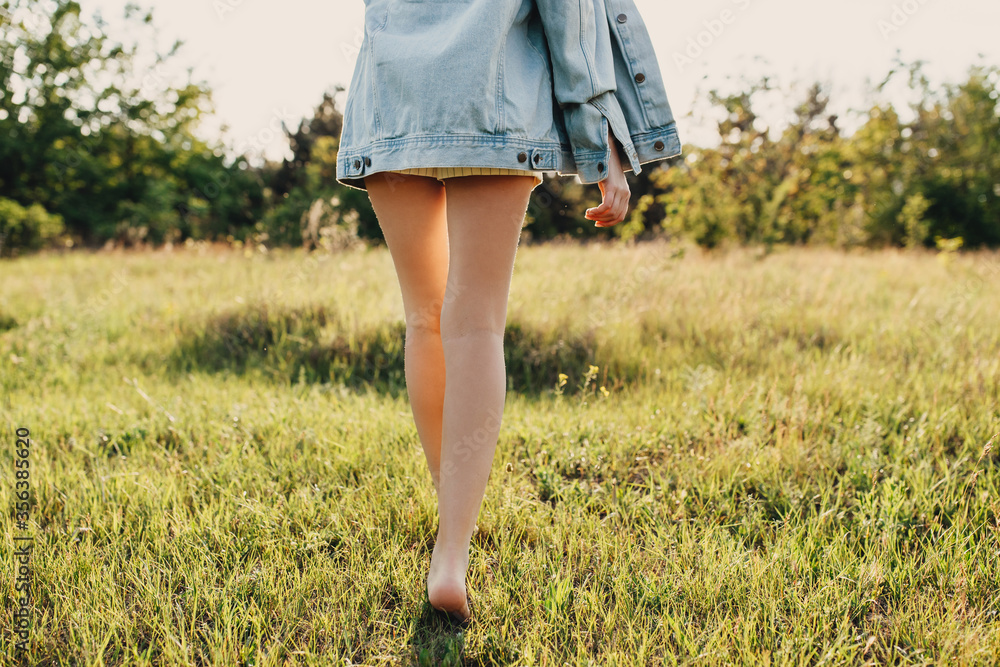 Φωτογραφία Barefoot legs of young woman in the park, walking on green grass.