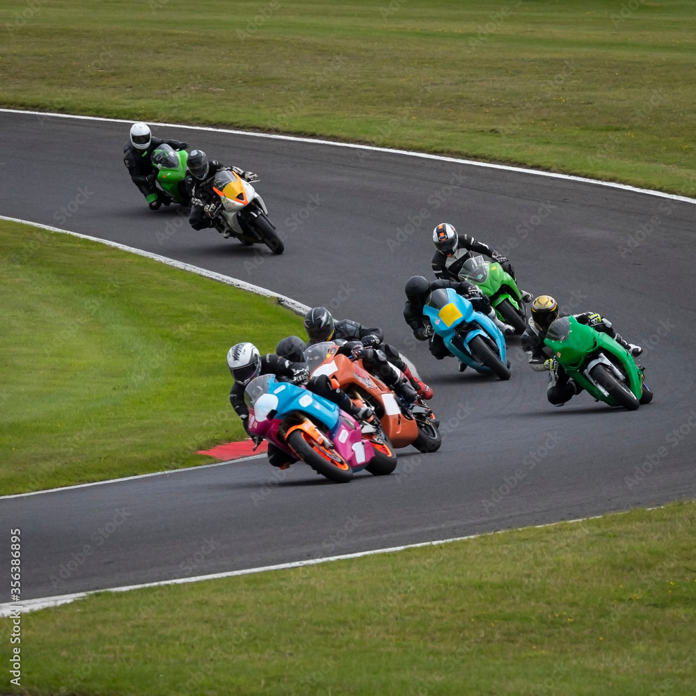 A panning shot of multiple racing bikes cornering on a track