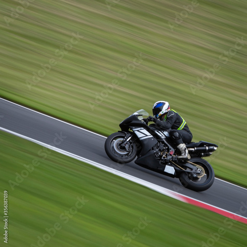 A panning shot of a black racing bike cornering on a track © SnapstitchPhoto