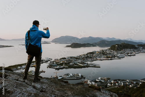 Traveller is taking pictures of scenic norwegian city view from the mountain. Travel and hiking concept