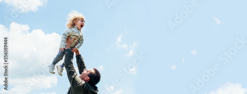 Joyful dad and daughter are playing outdoors in the park. The concept of a happy family. Dad with a baby. Banner