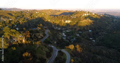 Aerial view over the Mulholland drive and Laurel Canyon, on a warm and sunny, spring evening, in the Rich and Famous homes, Hollywood Hills, Los Angeles, California, USA - Forward Dolly, drone shot photo