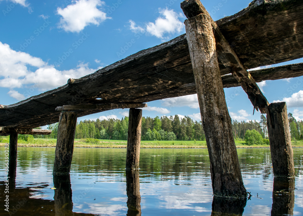 landscape with an old wooden footbridge in a small forest lake landscape with an old wooden footbridge in a small forest lake