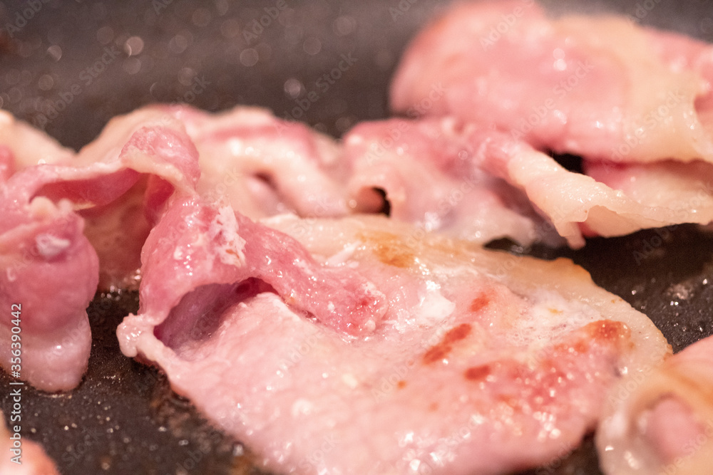 Bacon cooking in a frying pan. Close up with out of focus elements Bacon cooking in a frying pan. Close up with out of focus elements