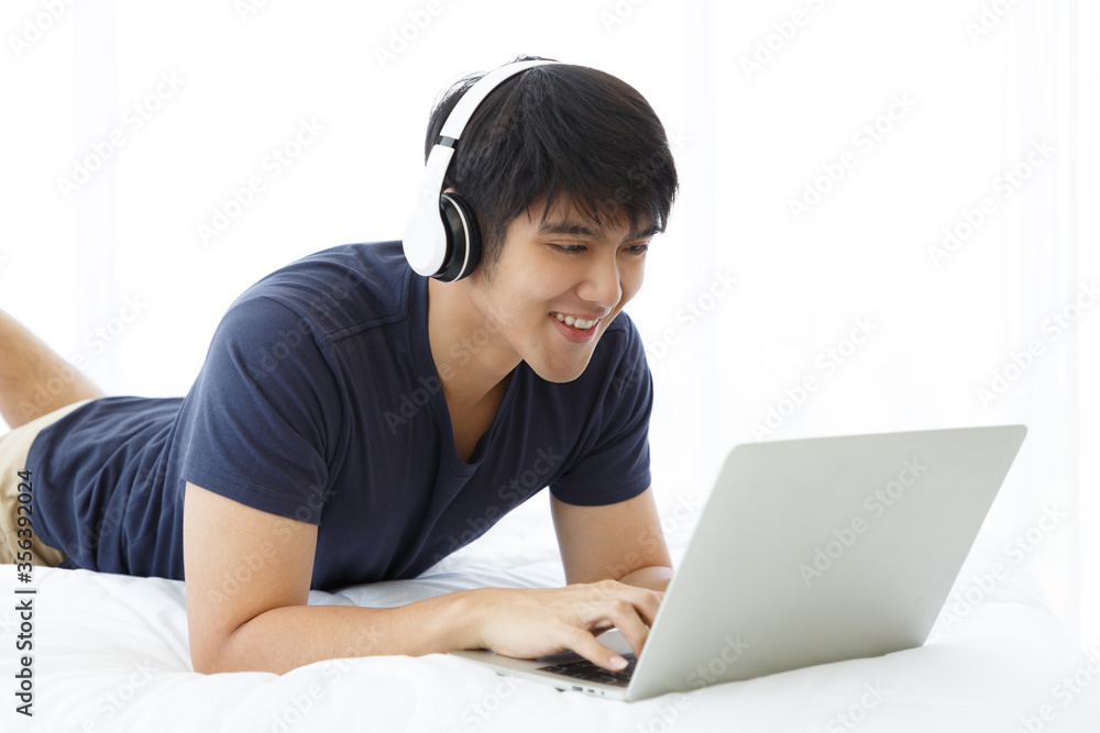 Happy man using Laptop computer and checking good News in the Bedroom. COPY SPACE. Trading. Watching Movie. WORK FROM HOME WFH Concept. Happy man using Laptop computer and checking good News in the Bedroom. COPY SPACE. Trading. Watching Movie. WORK FROM HOME WFH Concept.