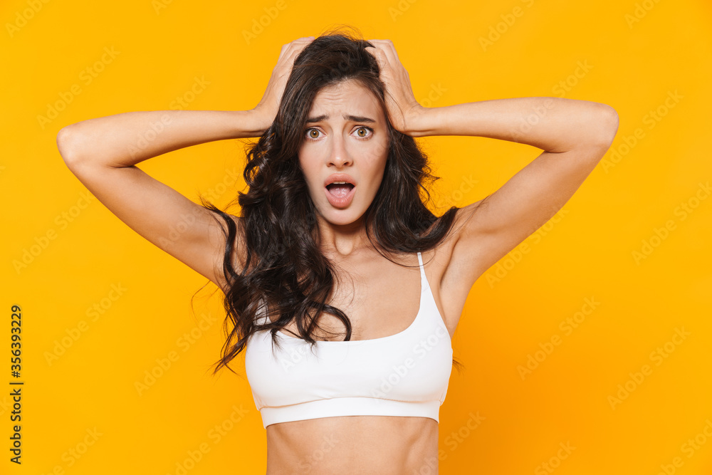 Image of young shocked woman grabbing her head and looking at camera Image of young shocked woman grabbing her head and looking at camera