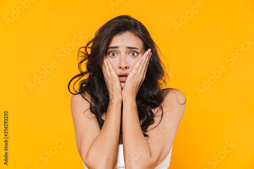 Image of scared young woman covering her face and looking at camera