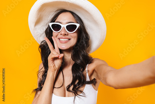 Image of cheerful woman gesturing peace sign while taking selfie photo