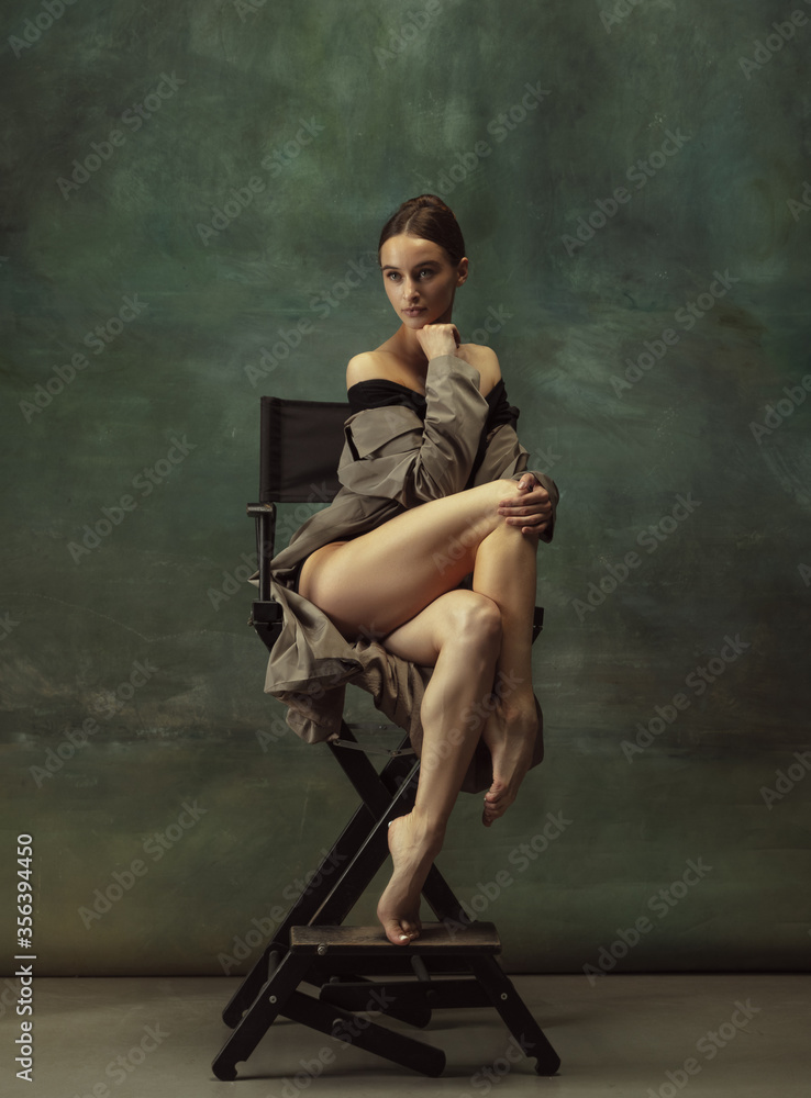 Beautiful portrait. Graceful classic ballerina dancing, posing isolated on dark studio background. Stylish trench coat. Grace, movement, action and motion concept. Looks weightless, flexible. Beautiful portrait. Graceful classic ballerina dancing, posing isolated on dark studio background. Stylish trench coat. Grace, movement, action and motion concept. Looks weightless, flexible.