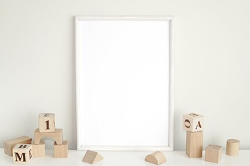 White frame mockup for nursery or kids room, blank photo frame and wooden cubes.