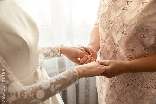 Bride and mother holding hands at wedding day