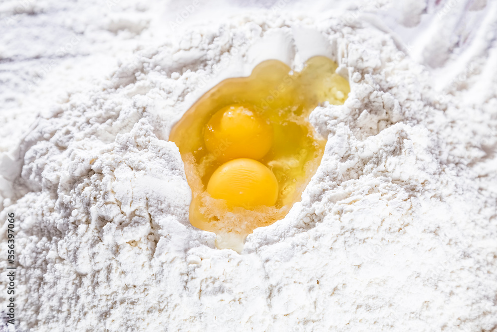 Baking scenery with a heap of wheat white flour for kneading dough for pasta or pizza with a raw egg on top. Close up. Homemade baking concept. Baking scenery with a heap of wheat white flour for kneading dough for pasta or pizza with a raw egg on top. Close up. Homemade baking concept.