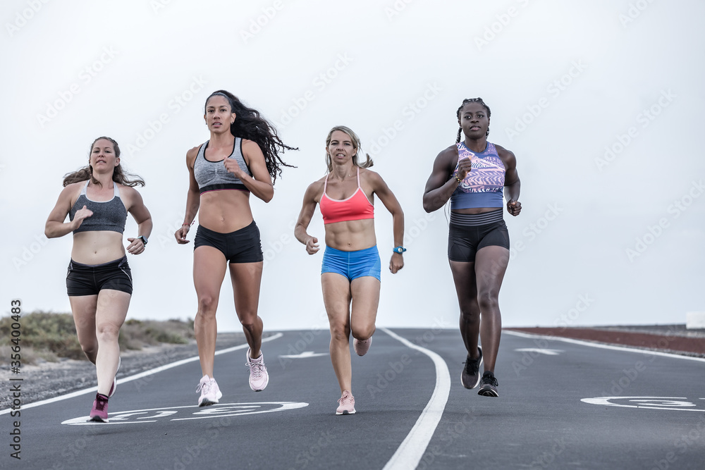 Muscular diverse women running on road