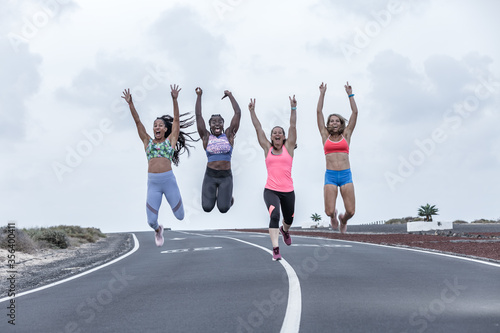 Happy diverse sportswomen jumping on road