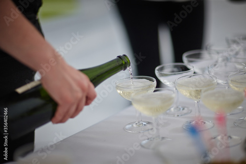 the waiter pours champagne into the glasses in a restaurant at a wedding