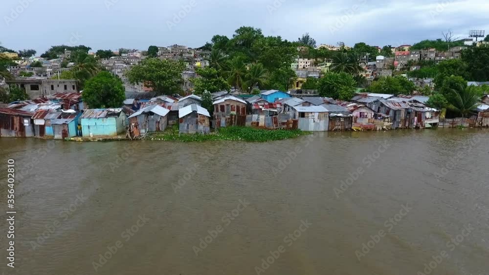 Aerial, tracking, drone shot over the Rio Ozama river, overlooking houses on the shore, in Santo Domingo, Dominican Republic