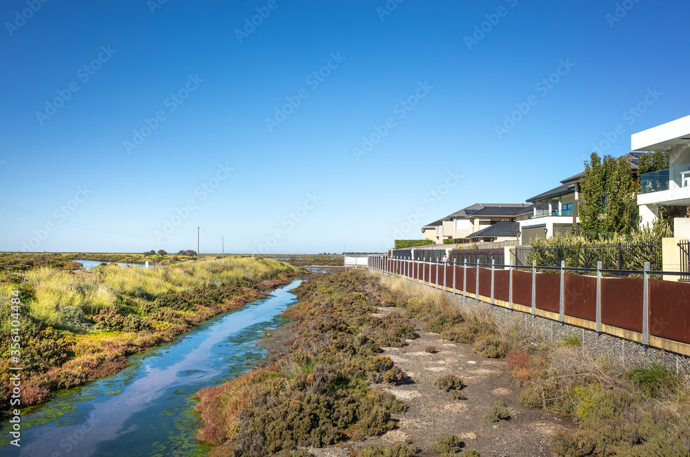 Wetlands and a row of residential houses.Skeleton Creek at Sanctuary Lakes, Melbourne, VIC Australia.