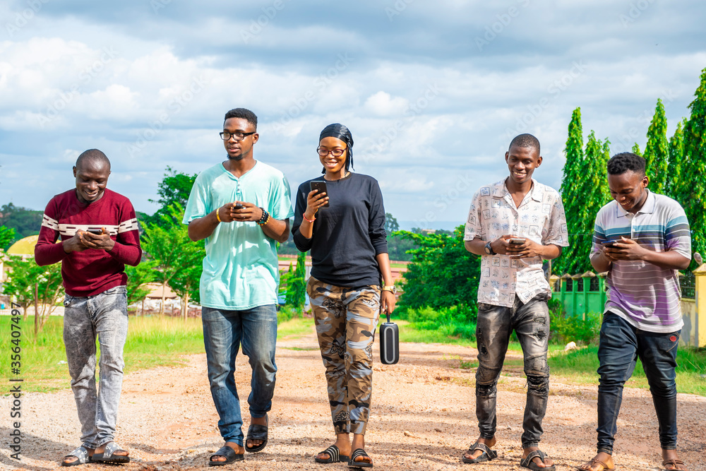 group of friends, walking, laughing, having fun, using their mobile phones group of friends, walking, laughing, having fun, using their mobile phones