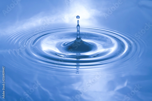 The water droplets fall on the water surface until the water spread out, creating beautiful ripples on the light blue water...