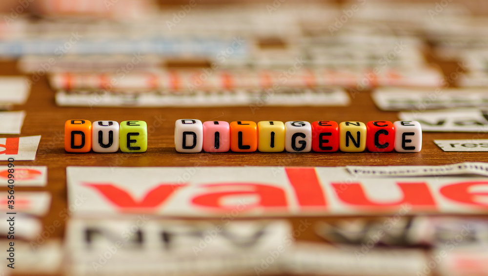 Colorful letter beads DUE DILIGENCE with common business-related title from newspaper cuts. Selective focus on beads only.