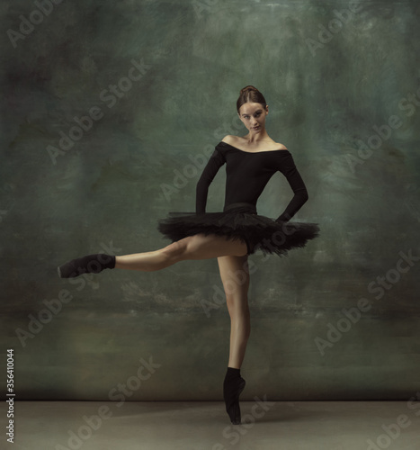 Beautiful portrait. Graceful classic ballerina dancing, posing isolated on dark studio background. Elegance black tutu. Grace, movement, action and motion concept. Looks weightless. Fashionable. © master1305