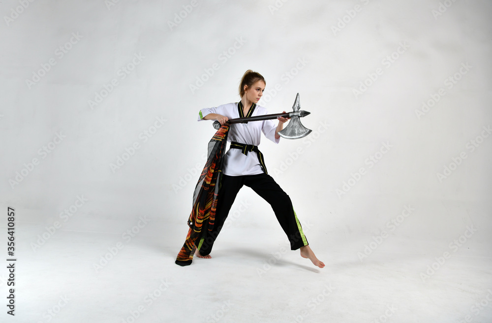 beautiful girl in a white-black suit does exercises with a battle ax and a scarf