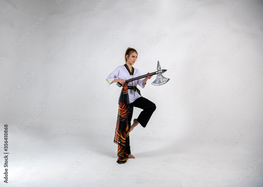 Fototapeta premium beautiful girl in a white-black suit does exercises with a battle ax and a scarf