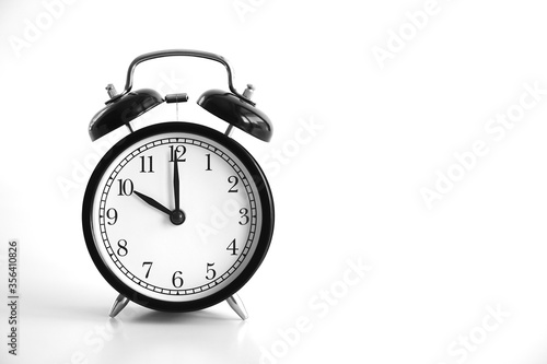 Black vintage alarm clock on table. White background. Wake up concept. An image of a retro clock showing 10:00 pm/am. 