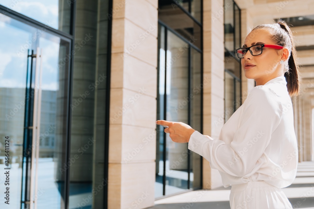 Portrait of a smiling glamorous lady in a business suit with glasses. Freelancer looks at client, discussion of project