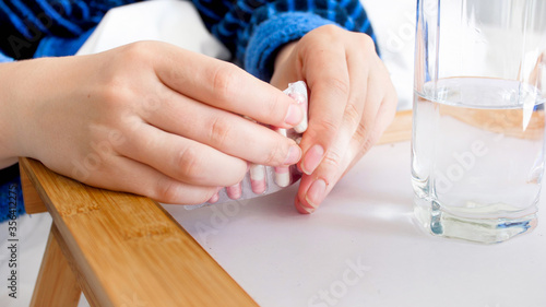 Closeup image of female hands opening pills