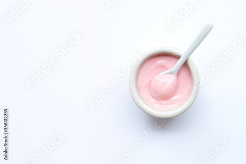 Ceramic bowl of pink strawberry yogurt on white