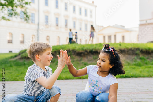 Two friendly dark-skinned and white children diverse positive boy and girl stand hugging. children concept photo
