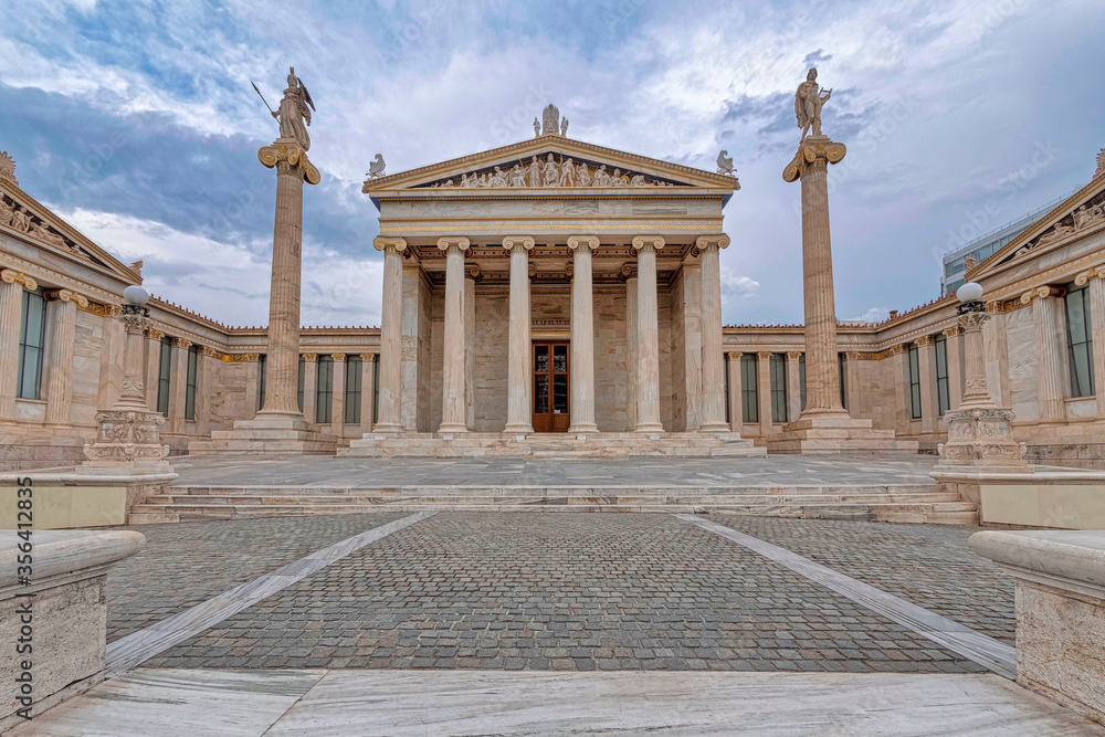 Athens Greece, the national academy classical building facade with Athena and Apollo statues standing on Ionian style columns under impressive sky