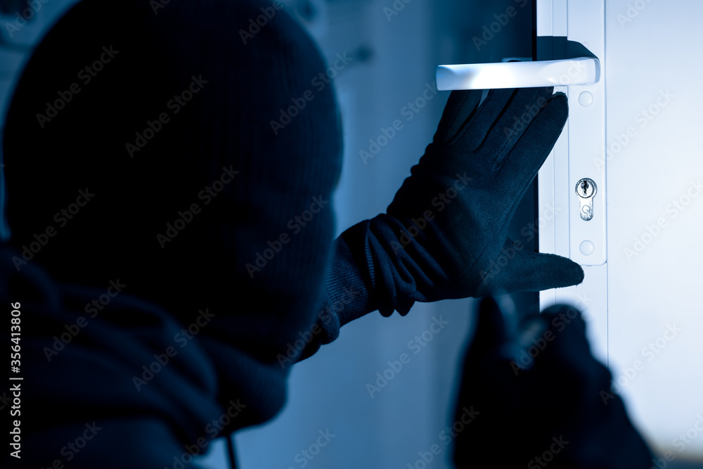 © Prostock-studio - Robber in black balaclava cracking door with metal picklock